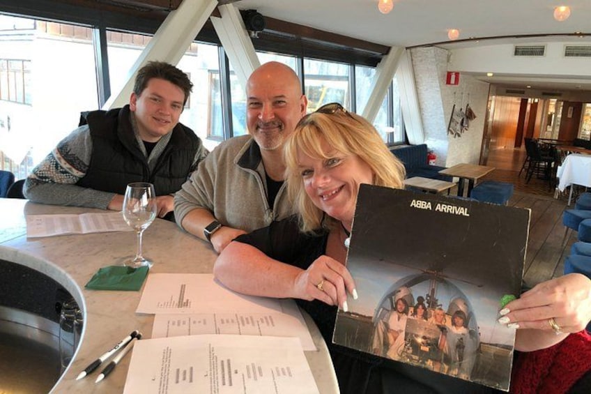 Un grupo de personas sentadas a una mesa con un menú, un vaso de agua y un menú con el texto 'ABB ARRIVAL'. 3