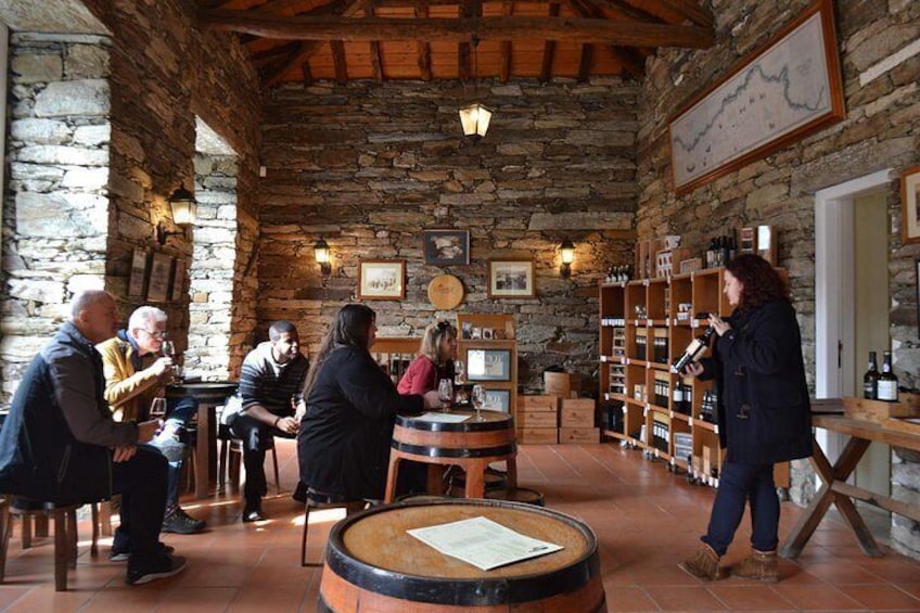 A rustic wine cellar with wooden barrels, shelves of wine bottles, and patrons seated at tables. 4