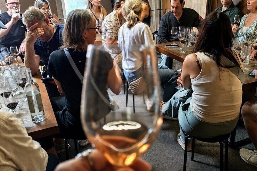 A group of people seated at a table in a restaurant, with wine glasses and bottles visible. 4