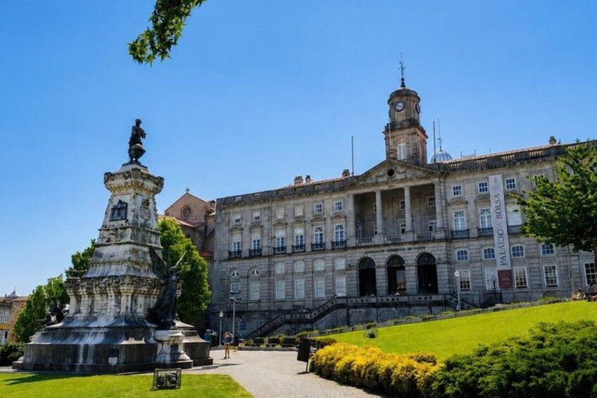 A historic building with a clock tower, a statue, and a well-maintained garden. 5