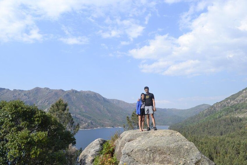 A couple standing on a rock overlooking a lake surrounded by mountains. 2