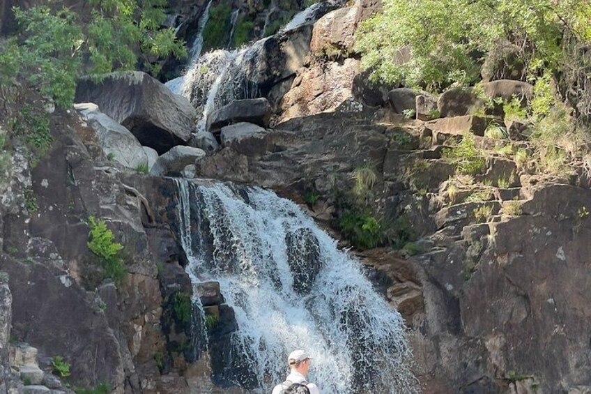 Ein Wasserfall stürzt über Felsen, umgeben von üppigem Grün. 3