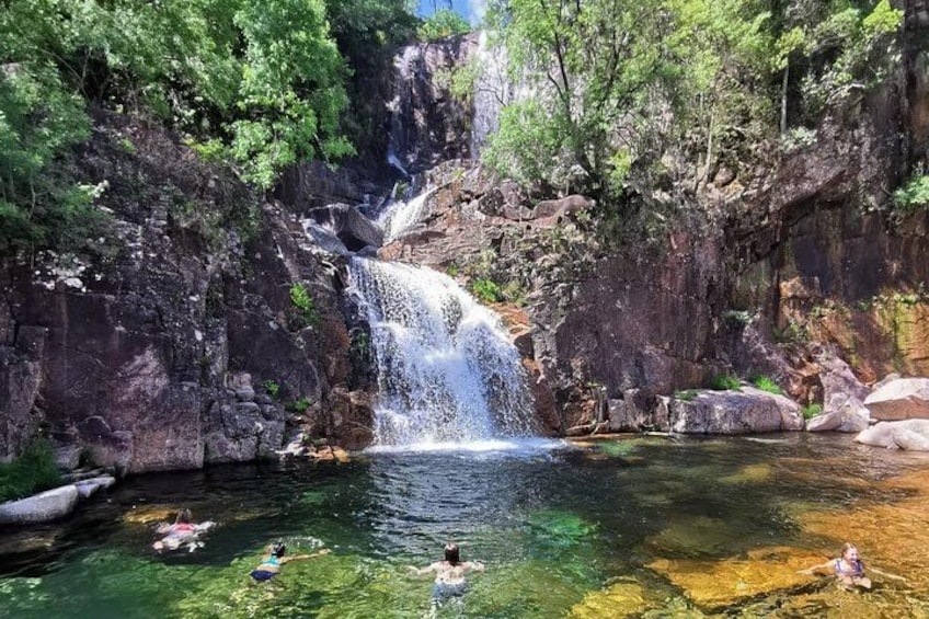 Ein Wasserfall, klares Wasser und Menschen, die schwimmen. 1
