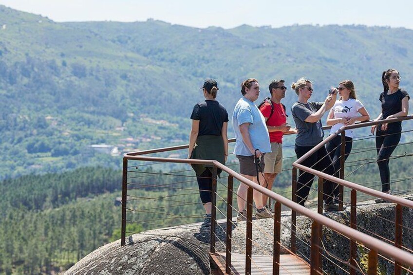 A group of people standing on a viewing platform overlooking a mountainous landscape. 3