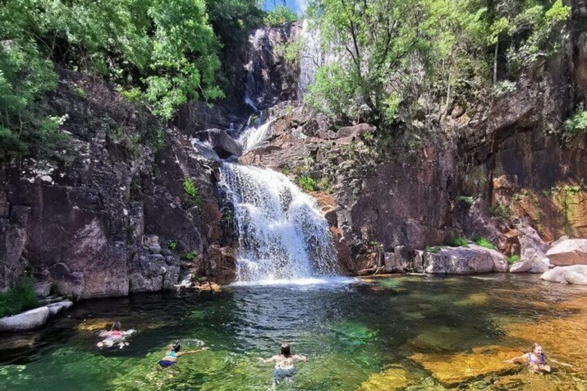 A waterfall, clear water, rocks, and greenery. 1