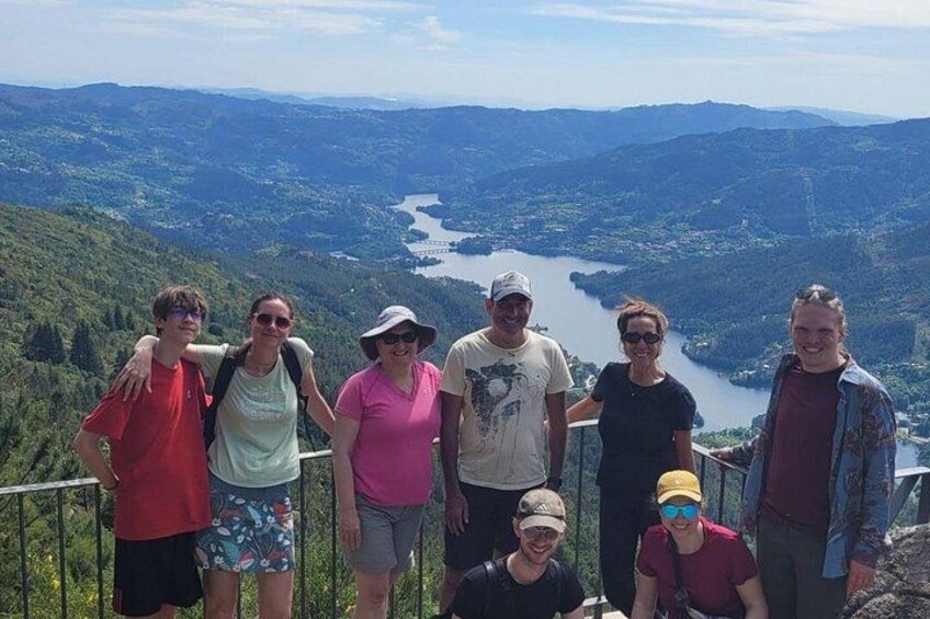 Eine Gruppe von Menschen steht auf einem Berg und blickt auf ein Tal mit einem Fluss. 4