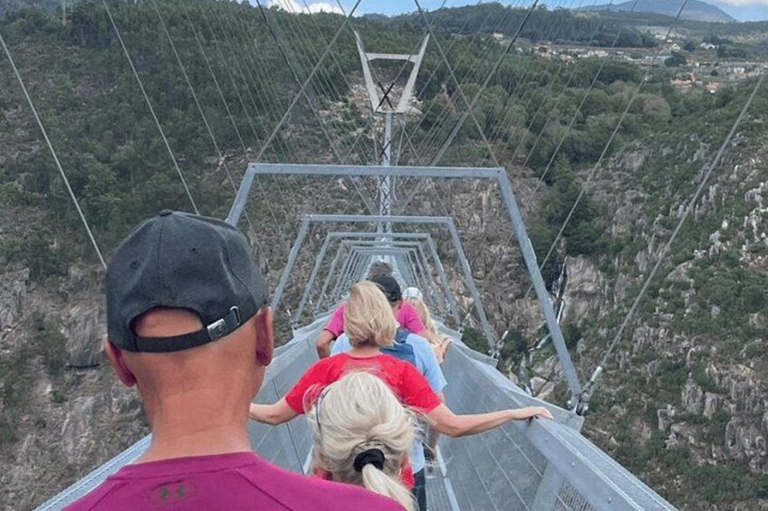 Un grupo de personas en un puente colgante, con un paisaje montañoso al fondo. 3