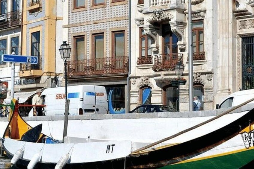 Un bote con las letras 'MT' en su costado, amarrado cerca de un edificio con balcones ornamentados y una señal de calle. 5