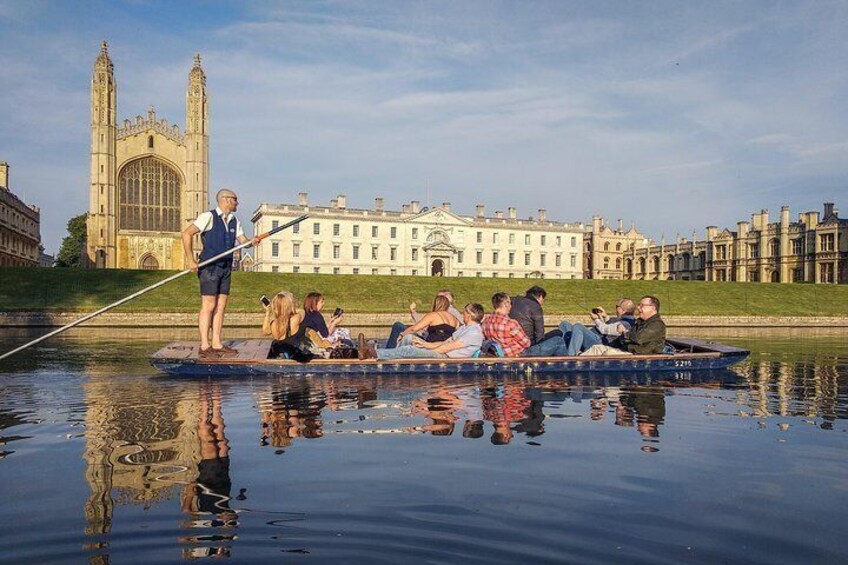 A group of people on a boat in a river with a large building in the background. 1