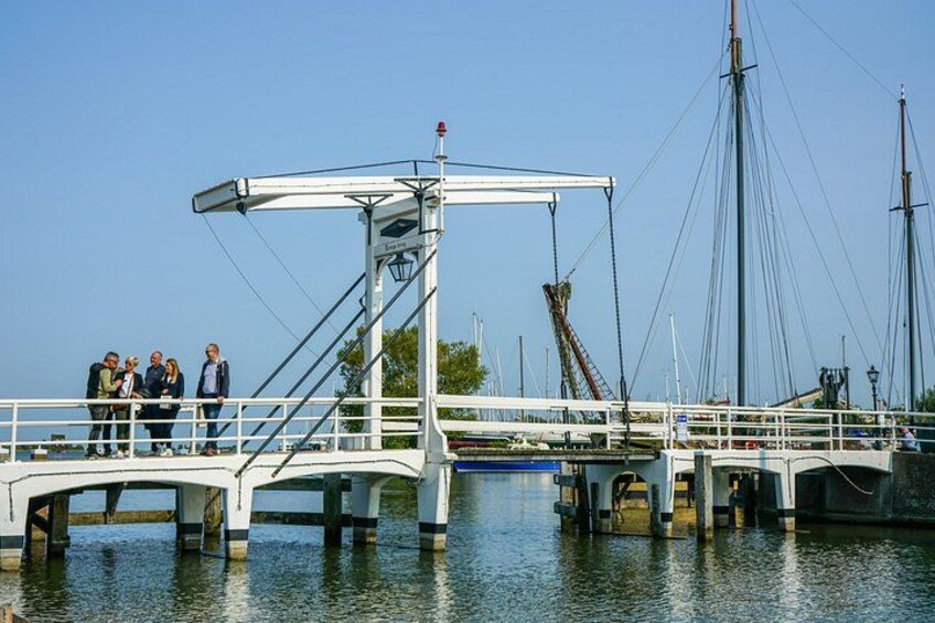 A white bridge with a pedestrian walkway over water, surrounded by boats and a clear sky. 2