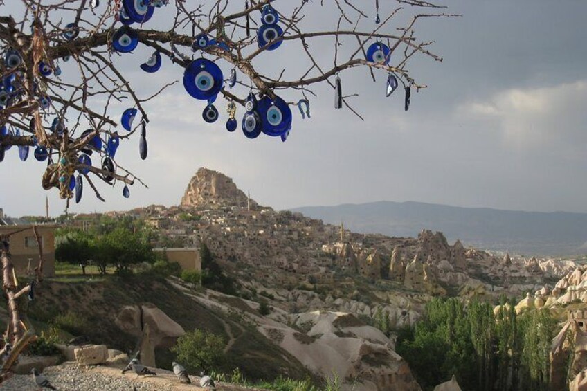 A rocky landscape with a village, a prominent rock formation, and a tree with blue decorations. 5