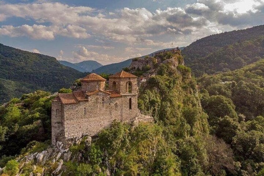 A historic stone castle perched on a hill surrounded by lush greenery. 2
