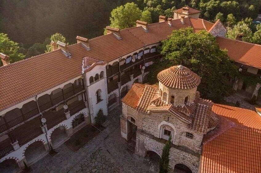 A historical building complex with red-tiled roofs, a central tower, and surrounding greenery. 3