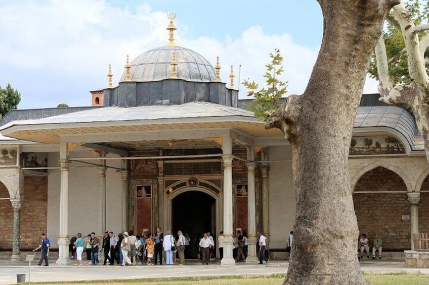 A historic building with a large dome and arches, surrounded by a crowd of people. 1