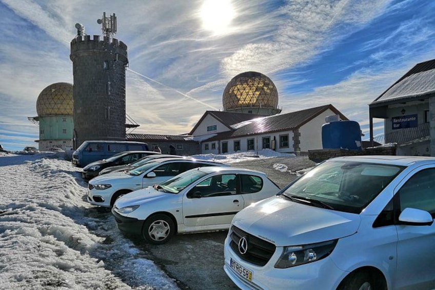 Et snækkedækket parkeringsområde med flere biler, et tårn og en bygning med en kuppel. 2