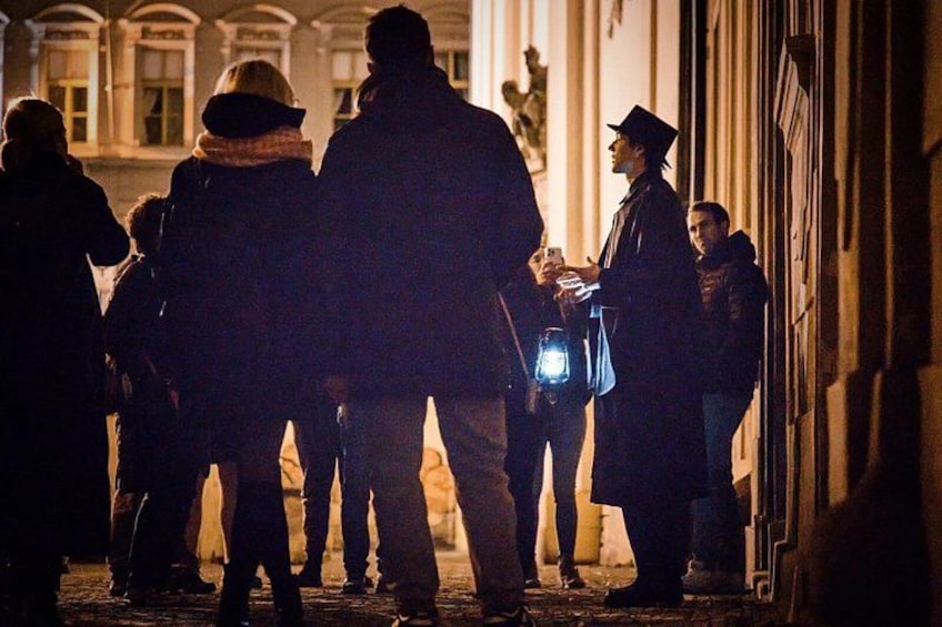 Un groupe de personnes se tient dans une rue, la nuit. Certaines d’entre elles tiennent des téléphones et une lampe de poche. 2
