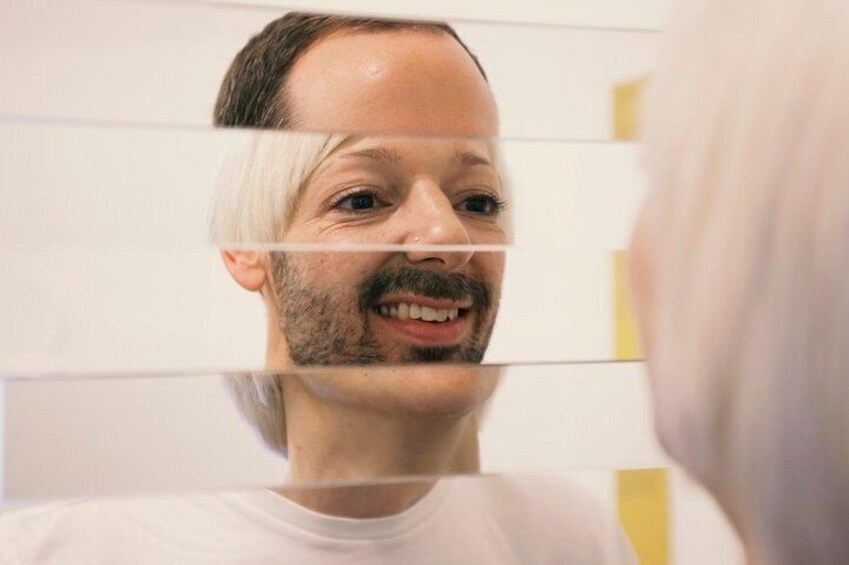 A person in a white shirt standing in front of a mirror with a reflection. 3
