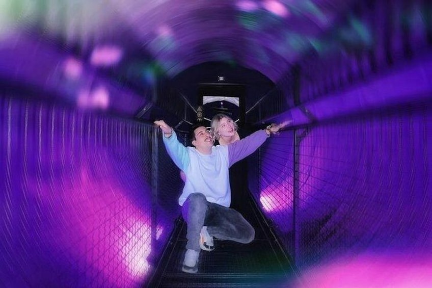 A person sliding down a purple-lit tunnel. 2
