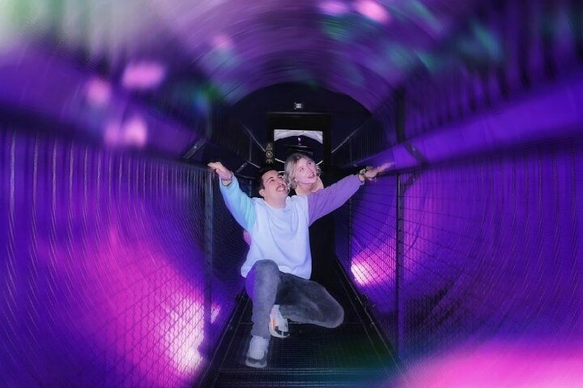 A person sliding down a purple-lit tunnel. 5