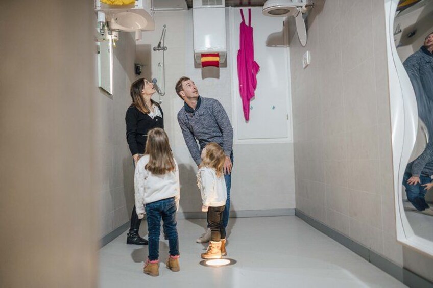 A modern bathroom with a white sink, a shower, and a toilet. There is a pink towel hanging on the wall. 2