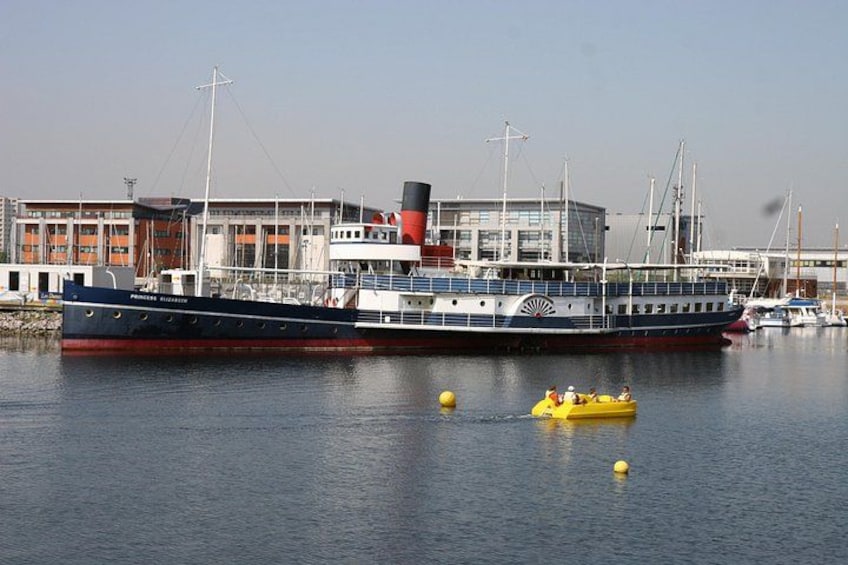 A large ship docked at a harbor with buildings in the background. 2