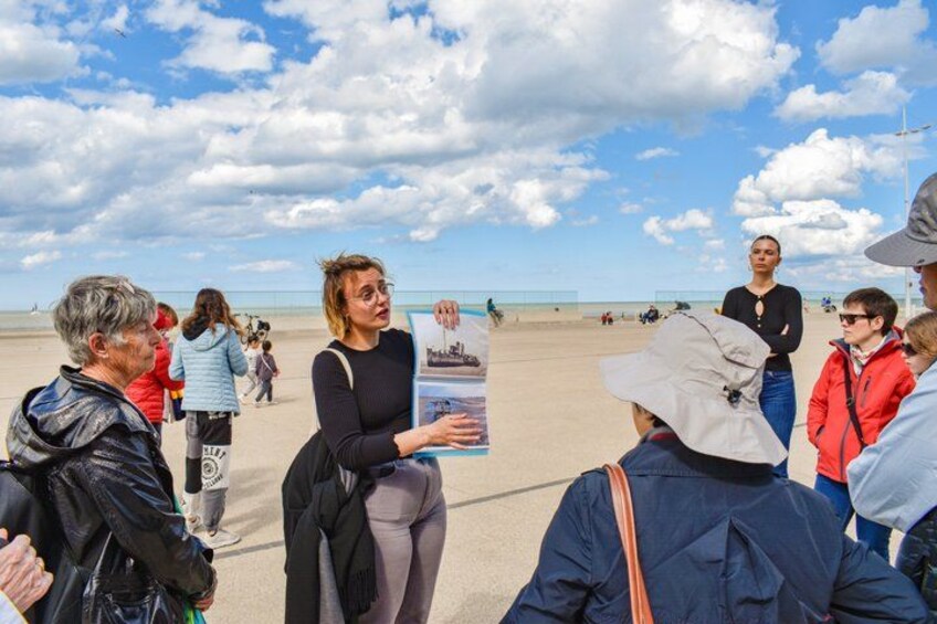 A group of people on a beach, some holding informational posters. 5