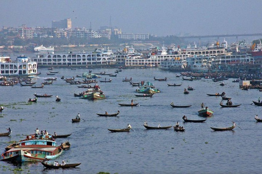 A busy river with numerous boats, a bridge, and buildings in the background. 3