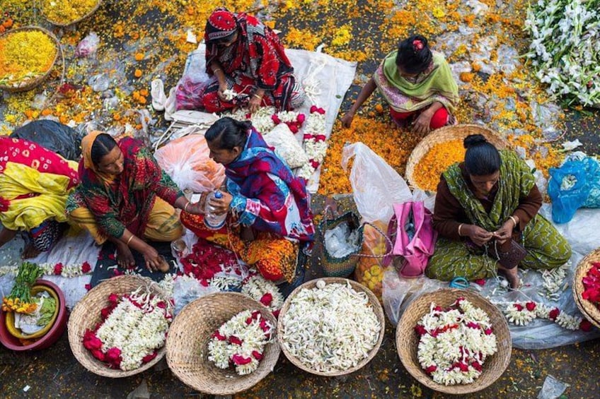 Vrouwen die bloemen op de grond rangschikken, met manden vol bloemen en verspreide bloemblaadjes. 3