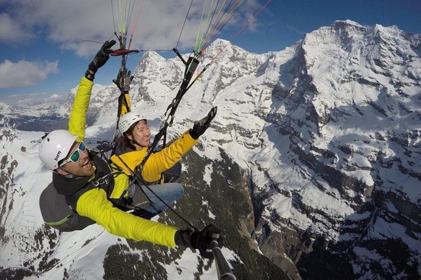 Two people paragliding over a snowy mountain range. 4