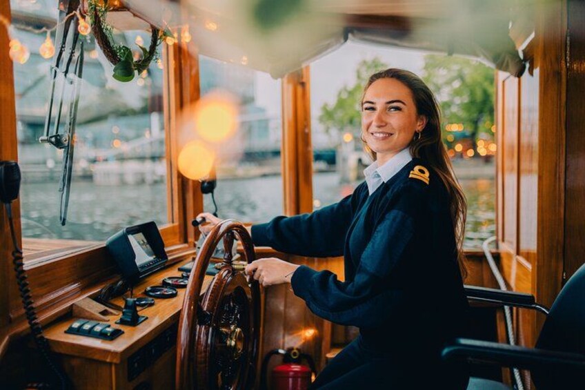 A person steering a boat, steering wheel, and control panel. 3