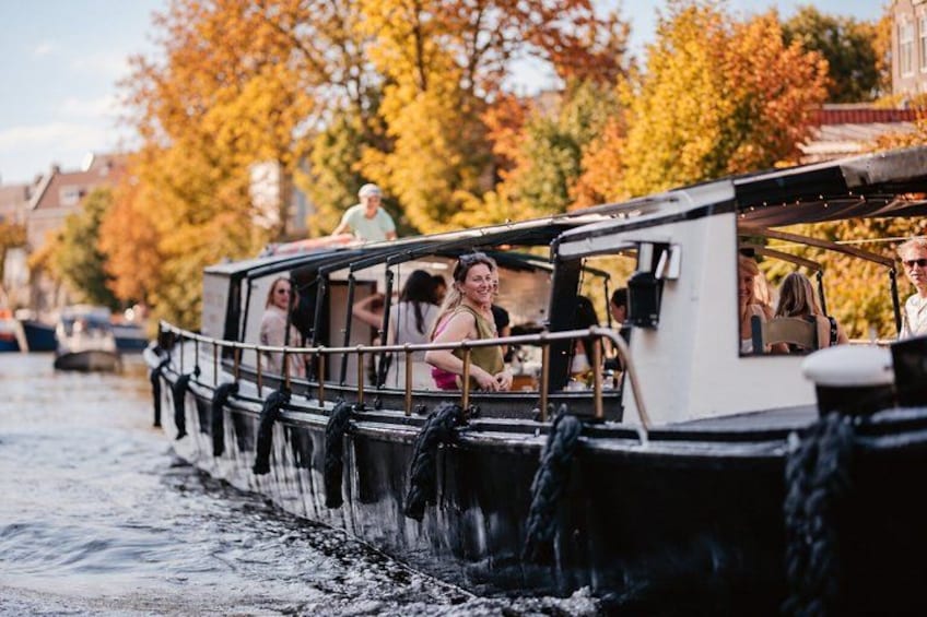 A boat with passengers, a canal, and autumn trees in the background. 5