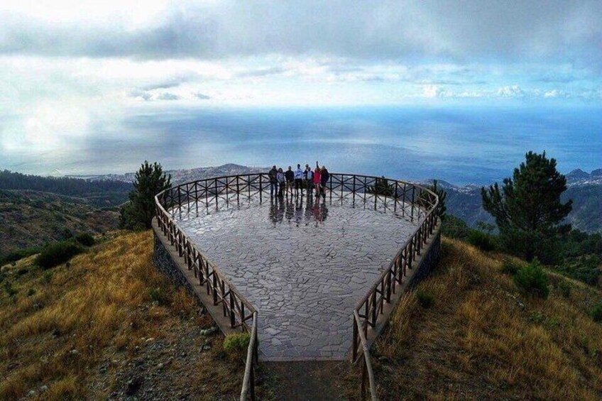 Una plataforma de piedra circular con barandilla, rodeada de terreno cubierto de hierba y con vistas a un paisaje lejano. 3