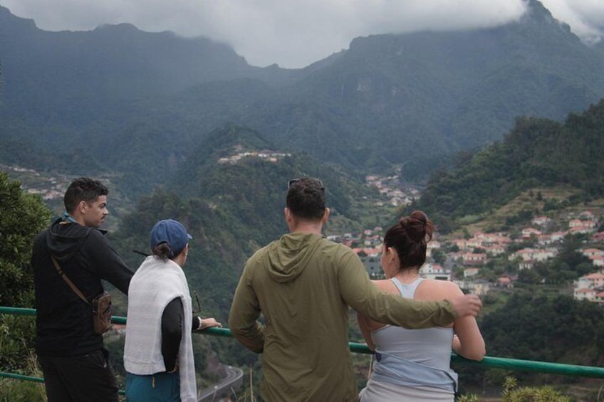 Un grupo de personas en una plataforma de observación con vistas a un paisaje montañoso y un pueblo en la ladera. 3