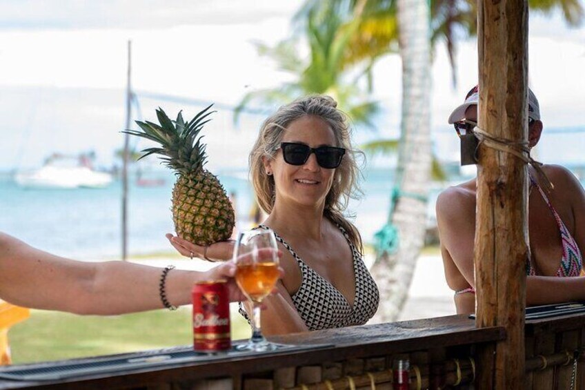 Una persona sosteniendo una piña y una cerveza en un bar de playa. 2