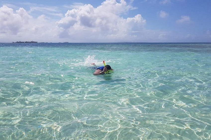 Una persona fa snorkeling in acque turchesi cristalline, con un'isola sullo sfondo. 5