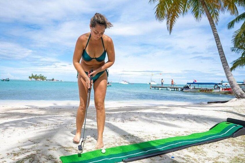 A person in a bikini on a sandy beach with a golf cart and a golf ball. 4