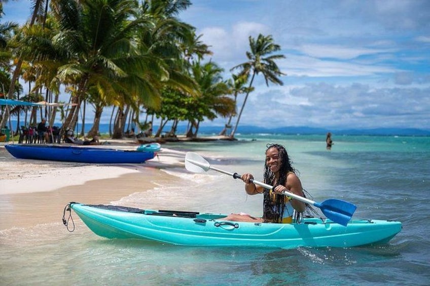 A person kayaking on a beach with palm trees and a clear sky. 5