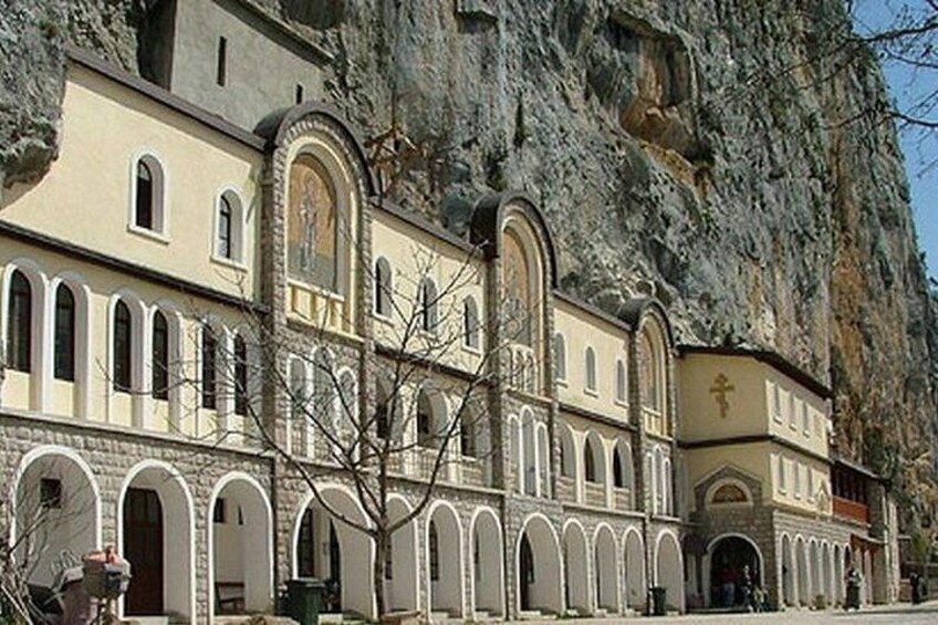 A church with arched windows and a large rock face behind it. 3