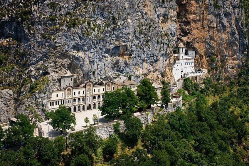 A monastery nestled in a rocky cliffside, surrounded by lush greenery. 4