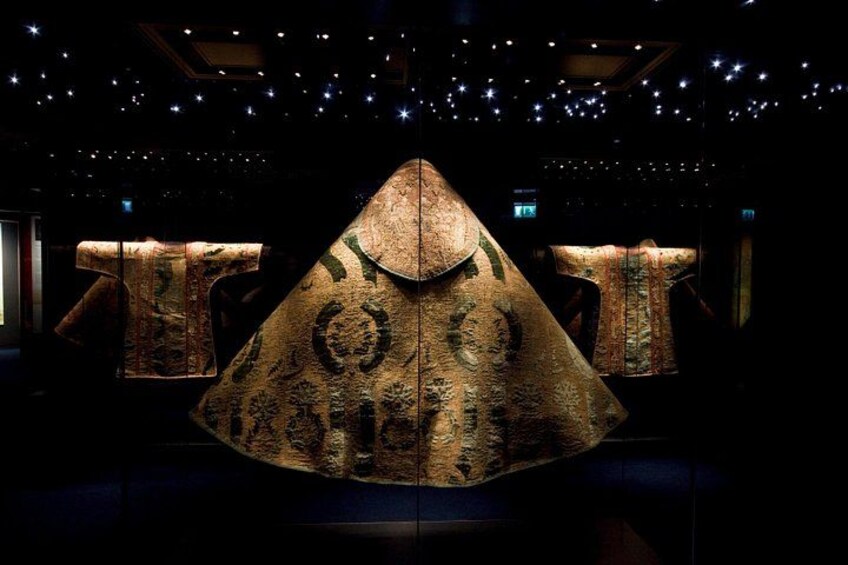 A large, illuminated, pyramid-shaped structure with intricate patterns, set in a dimly lit room with star-like ceiling decorations. 2