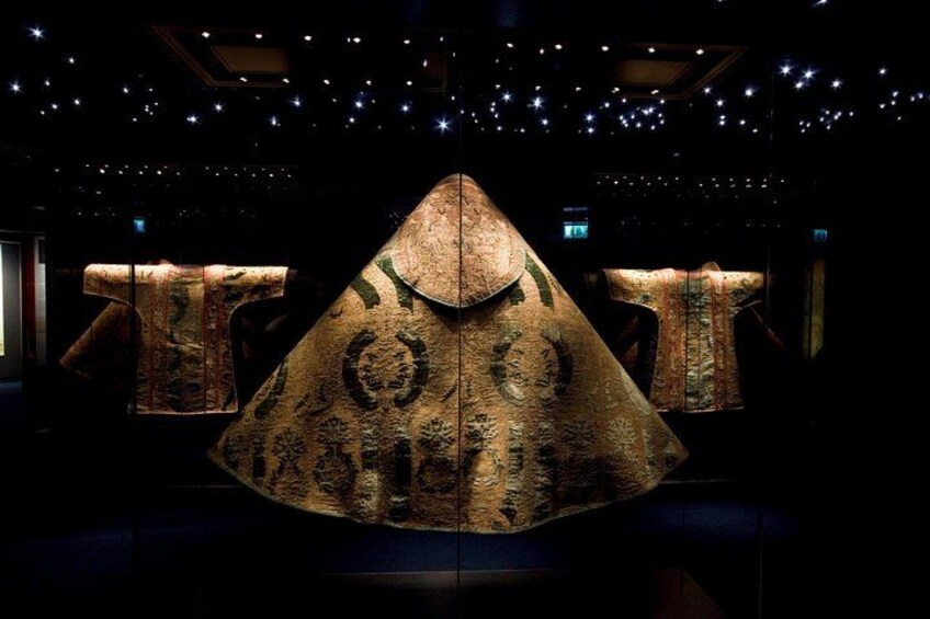 A large, ornate, triangular artifact displayed in a dimly lit room with starry ceiling. 3