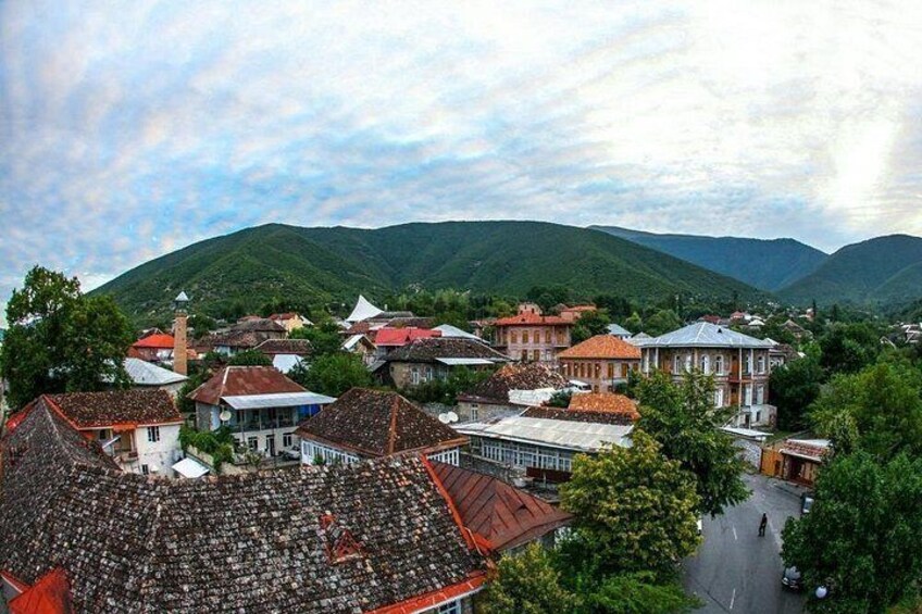 A town with buildings, a road, and green hills in the background. 4