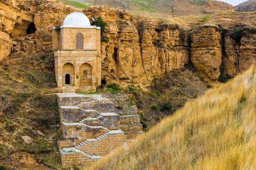 Una estructura histórica de piedra con una cúpula, ubicada en un paisaje rocoso con una escalera que lleva a ella. 5