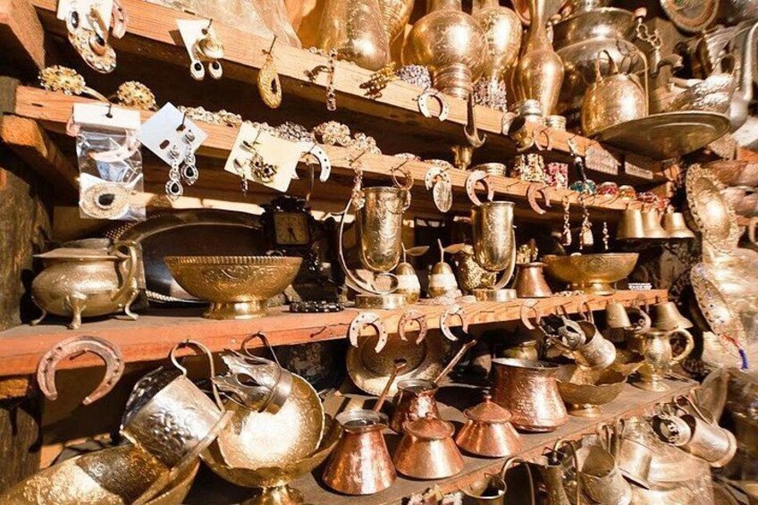 Una colección de objetos de metal antiguos, incluyendo cuencos, ollas y utensilios, exhibida en estanterías. 3