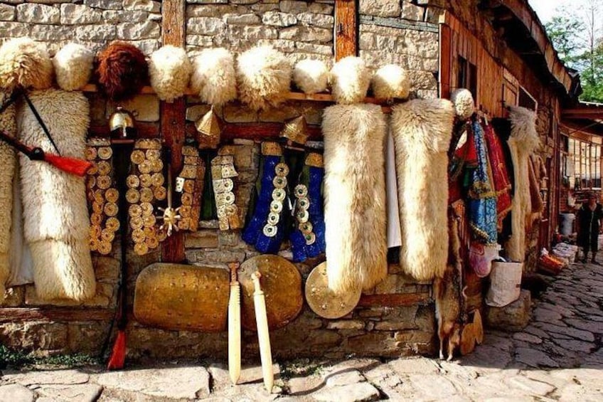 Edificio rústico con pieles de animales y ropa tradicional exhibidas afuera. 1