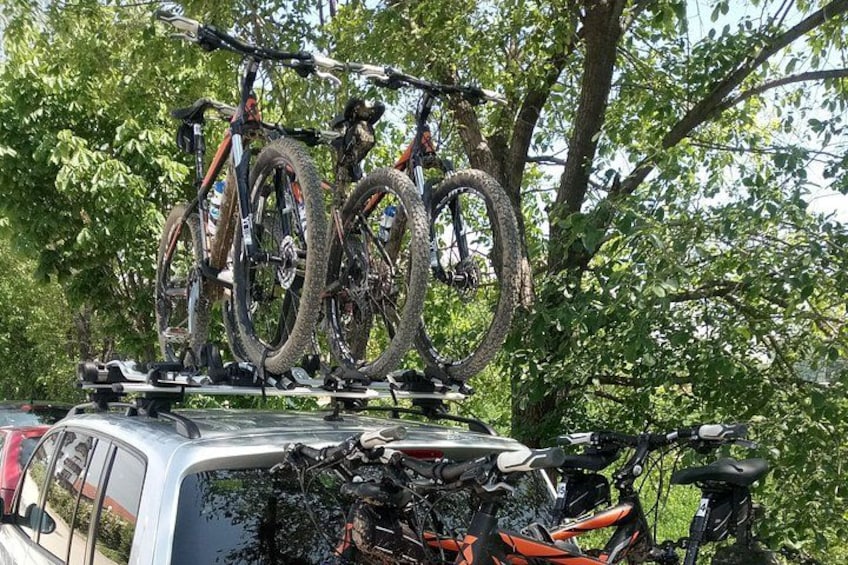 A vehicle with a roof rack carrying multiple bicycles and tires. 2