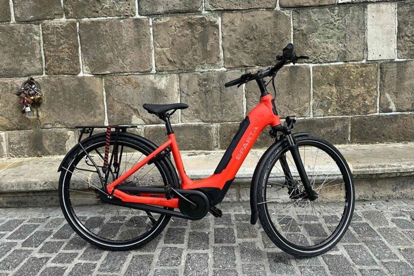A red electric bike parked against a stone wall. 2
