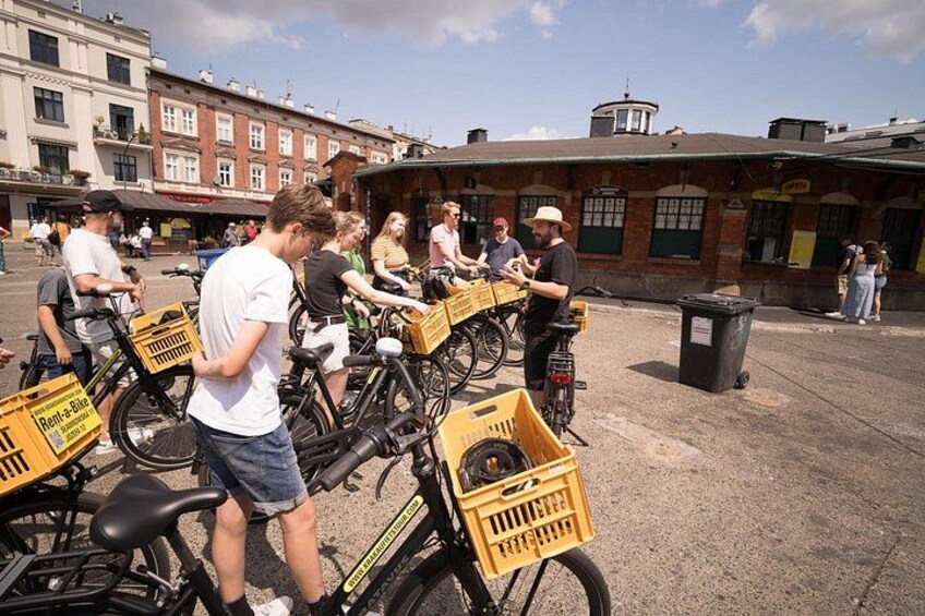 A group of people interacting with bicycles and yellow crates in an outdoor urban setting. 3