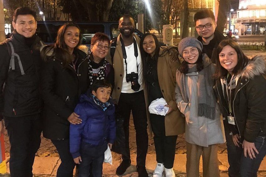 Un grupo de personas de pie en una acera por la noche. 2
