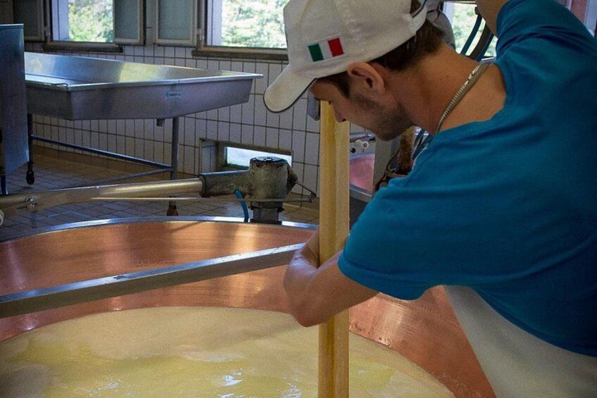 A person in a blue shirt and white cap working with a large copper pot in a kitchen setting. 3